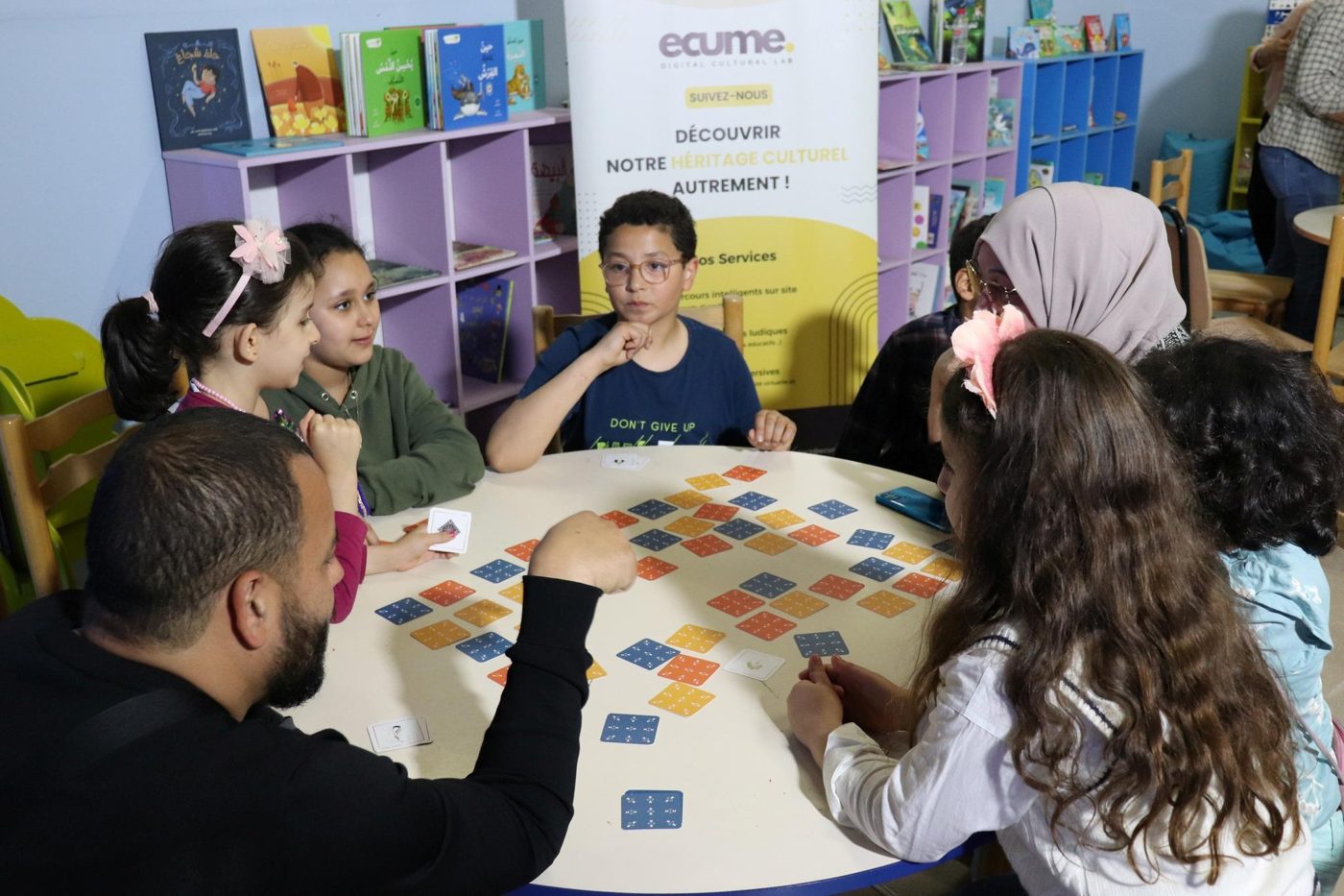 Enfants jouant au jeu de mémoire Farda w lkat okhteha autour d'une table